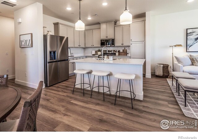 kitchen featuring stainless steel appliances, dark wood-type flooring, baseboards, a kitchen breakfast bar, and recessed lighting