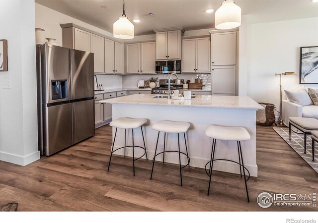 kitchen featuring appliances with stainless steel finishes, a kitchen breakfast bar, decorative light fixtures, light stone counters, and recessed lighting
