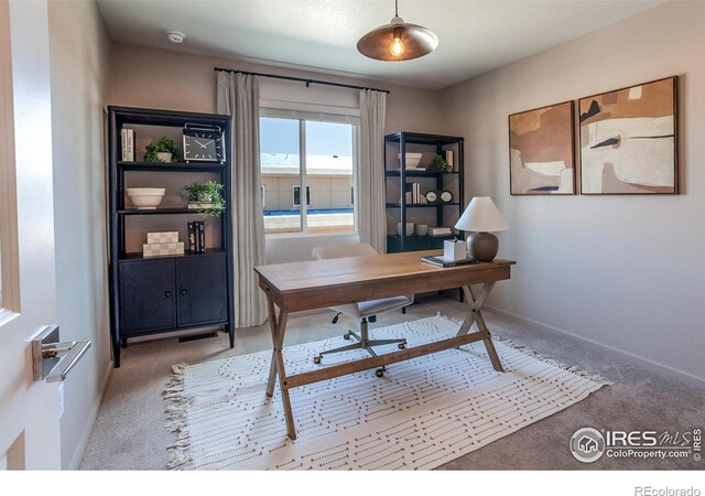 carpeted home office featuring baseboards