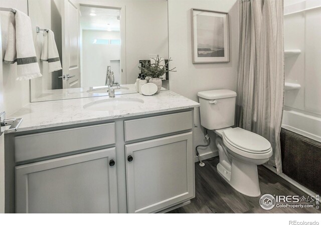 bathroom featuring vanity, toilet, wood finished floors, and shower / bath combo with shower curtain
