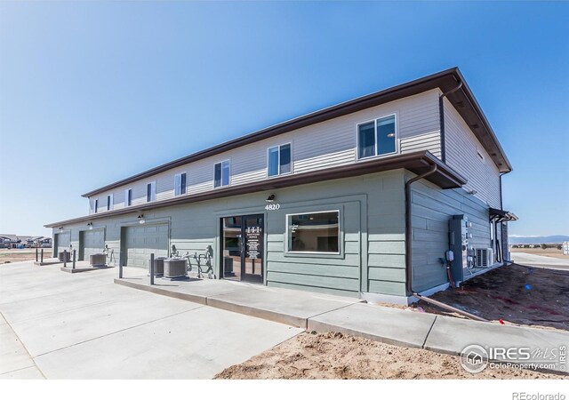 rear view of property featuring a garage and central air condition unit