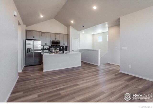kitchen with appliances with stainless steel finishes, gray cabinets, a sink, an island with sink, and decorative backsplash