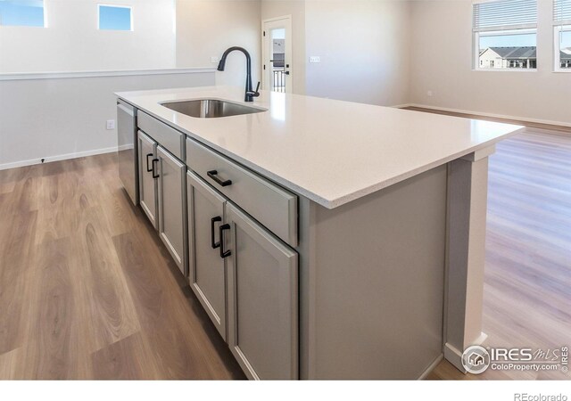 kitchen featuring a sink, gray cabinets, dishwasher, light wood-style floors, and light countertops