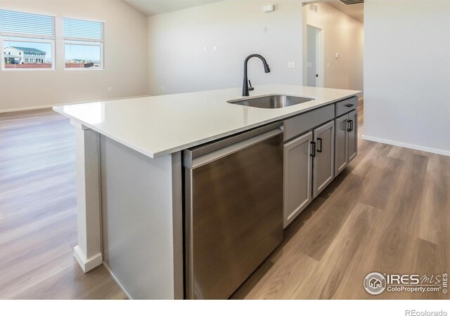 kitchen featuring a sink, dishwasher, light wood-style flooring, gray cabinetry, and light countertops