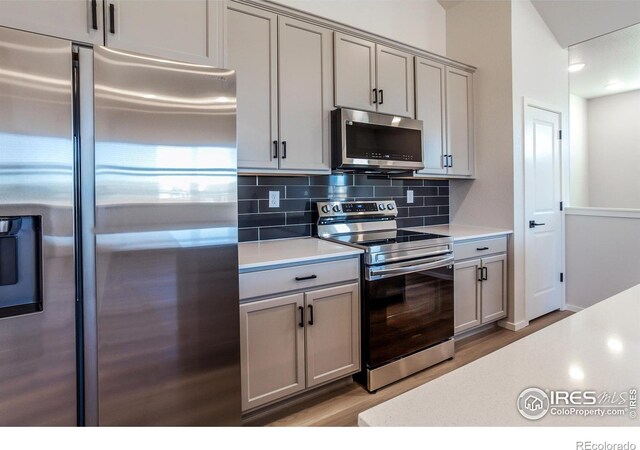 kitchen featuring stainless steel appliances, gray cabinetry, light countertops, and tasteful backsplash