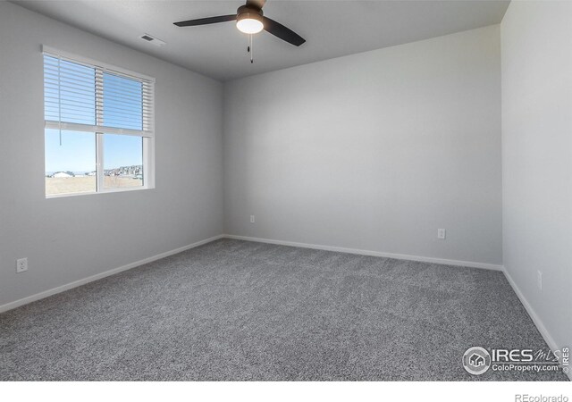 carpeted spare room featuring a ceiling fan and baseboards