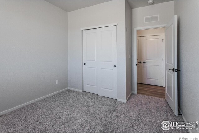 unfurnished bedroom featuring carpet, baseboards, and a closet