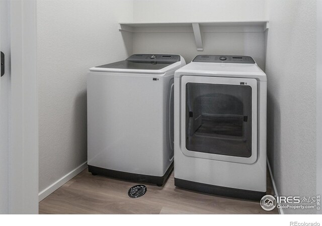 laundry area with washer and dryer, wood finished floors, and baseboards