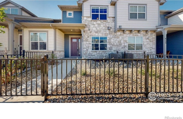 4157 Trapper Lake Dr, Loveland, CO 80538 - view of front of property featuring stone siding, a fenced front yard, and cooling unit