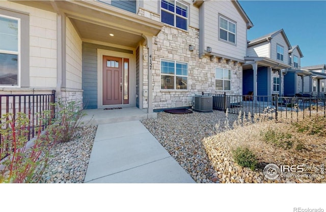 4157 Trapper Lake Dr, Loveland, CO 80538 - property entrance with stone siding, cooling unit, and fence