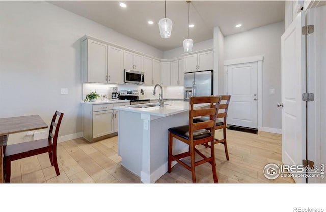 4157 Trapper Lake Dr, Loveland, CO 80538 - kitchen featuring appliances with stainless steel finishes, a sink, light wood-type flooring, an island with sink, and light countertops