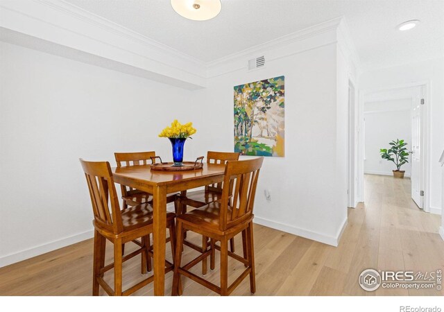 dining room featuring crown molding, light wood-style floors, baseboards, and recessed lighting