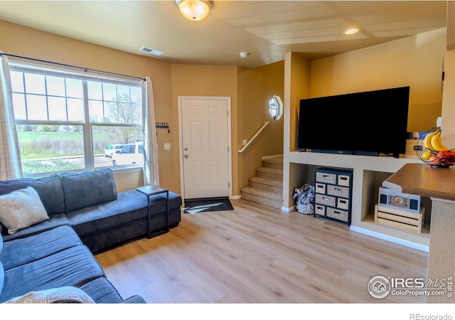 living area with stairway, wood finished floors, and baseboards