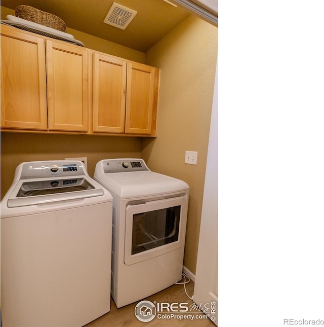 clothes washing area featuring washer and dryer and cabinet space