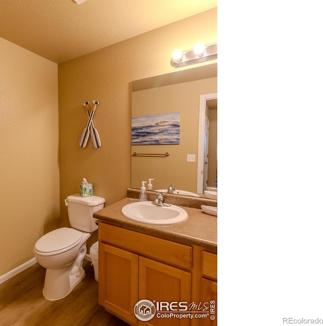 bathroom featuring toilet, wood finished floors, and vanity