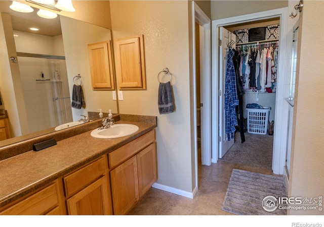 bathroom featuring a stall shower, a spacious closet, vanity, and baseboards