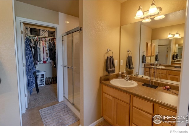 full bath featuring a stall shower, a spacious closet, and vanity