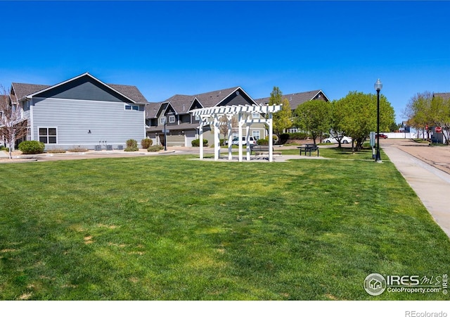 view of community featuring a pergola and a yard