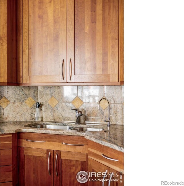 kitchen with light stone counters, backsplash, and a sink