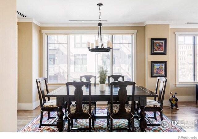 dining space with baseboards, wood finished floors, and crown molding