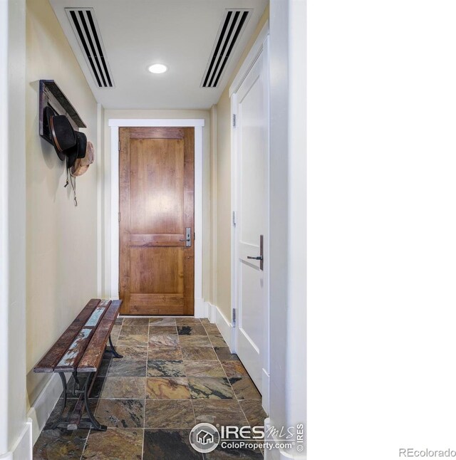 doorway featuring stone finish flooring, baseboards, and recessed lighting
