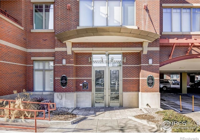 doorway to property with brick siding, french doors, and covered parking
