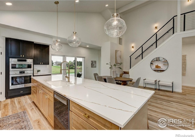 5304 Vardon Way, Fort Collins, CO 80528 - kitchen with high vaulted ceiling, dishwashing machine, double oven, light stone counters, and light wood-style floors