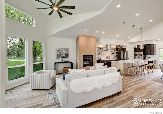 5304 Vardon Way, Fort Collins, CO 80528 - living area featuring high vaulted ceiling, a fireplace, ceiling fan, healthy amount of natural light, and light wood-style floors