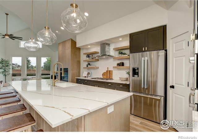 5304 Vardon Way, Fort Collins, CO 80528 - kitchen with appliances with stainless steel finishes, wall chimney range hood, vaulted ceiling, light stone countertops, and light wood-style floors