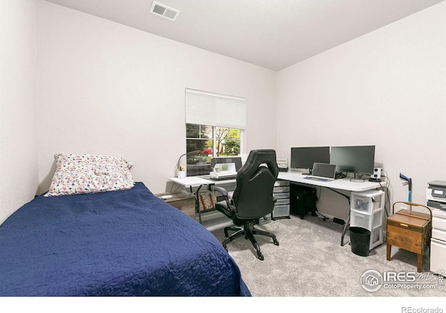 bedroom with light colored carpet and a desk