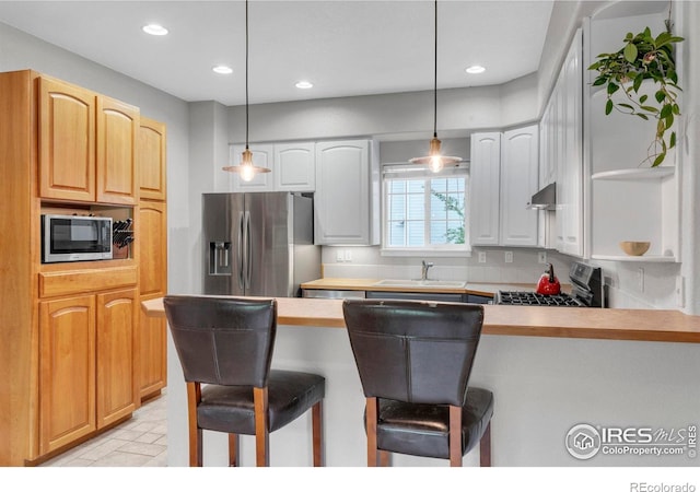1369 Padfield Pl, Erie, CO 80516 - kitchen with stainless steel appliances, a sink, recessed lighting, a breakfast bar, and a peninsula