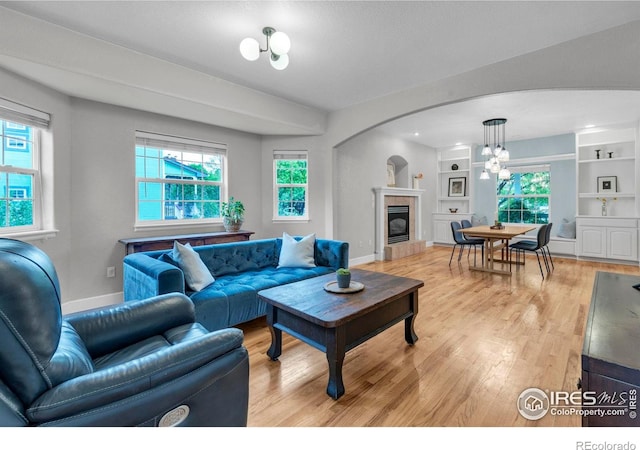 1369 Padfield Pl, Erie, CO 80516 - living room with light wood finished floors, a fireplace, arched walkways, and plenty of natural light