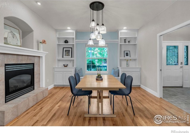 1369 Padfield Pl, Erie, CO 80516 - dining room featuring wood finished floors, a tiled fireplace, baseboards, and recessed lighting