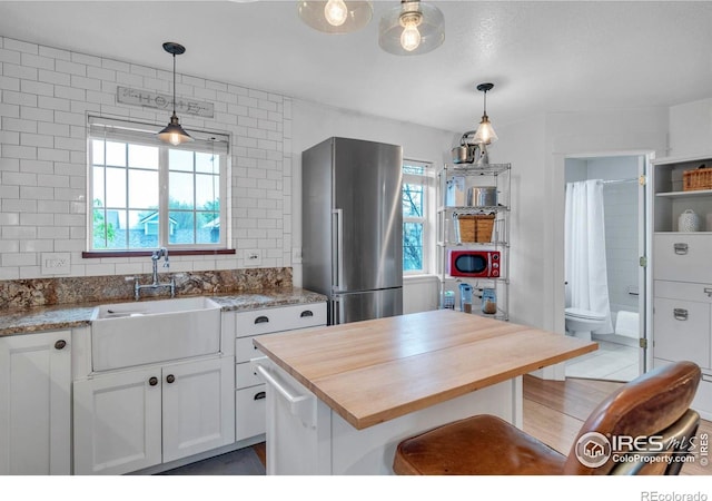 1369 Padfield Pl, Erie, CO 80516 - kitchen with wooden counters, high quality fridge, a sink, white cabinets, and hanging light fixtures
