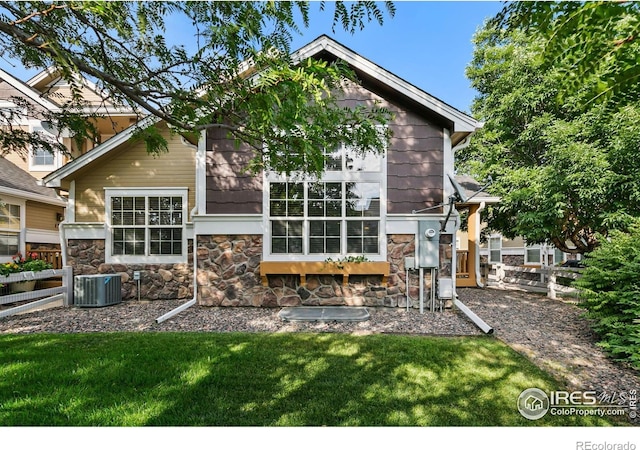 rear view of house with stone siding and central AC