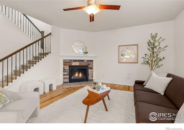 687 Jarvis Dr, Erie, CO 80516 - living area featuring wood finished floors, a ceiling fan, stairway, a stone fireplace, and baseboards