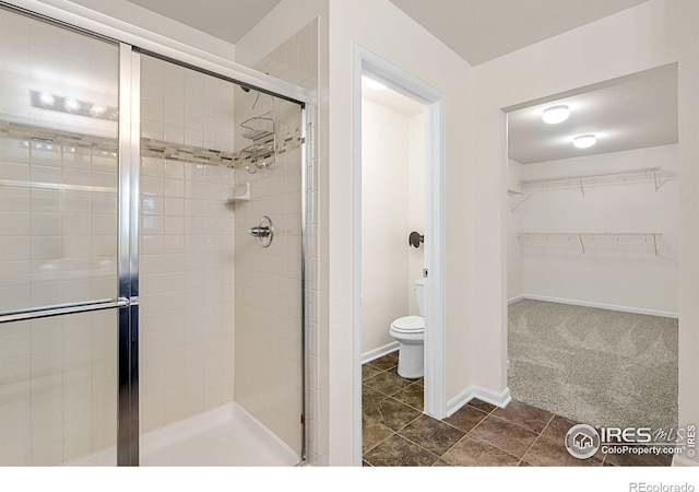 687 Jarvis Dr, Erie, CO 80516 - bathroom featuring toilet, a shower stall, a spacious closet, tile patterned floors, and baseboards