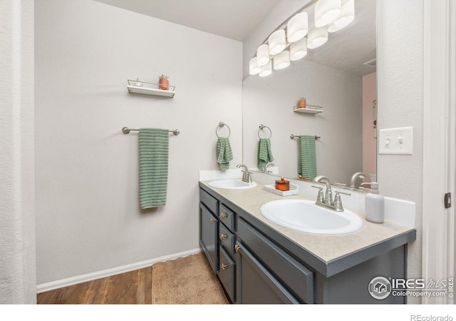 bathroom featuring double vanity, wood finished floors, and baseboards