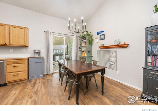 dining area with a chandelier, light wood-style flooring, high vaulted ceiling, and baseboards