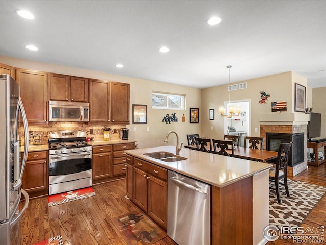 569 Jackson St, Lafayette, CO 80026 - kitchen with stainless steel appliances, a sink, dark wood-style floors, brown cabinets, and backsplash