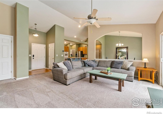 living room featuring arched walkways, carpet flooring, a ceiling fan, baseboards, and high vaulted ceiling