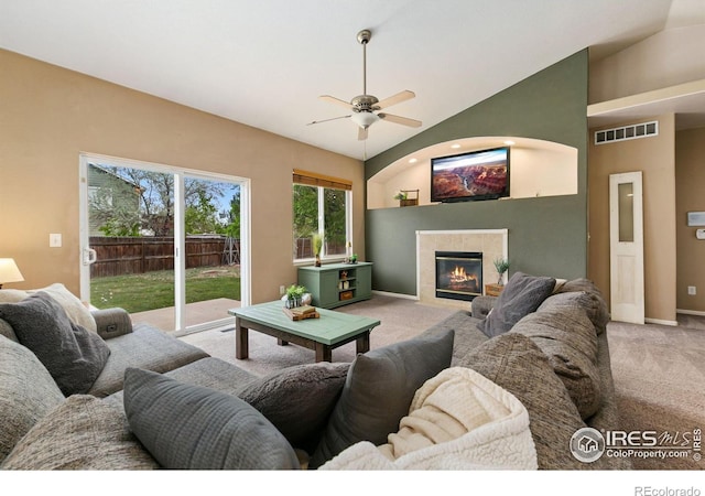 living area featuring carpet flooring, lofted ceiling, a ceiling fan, a tiled fireplace, and baseboards