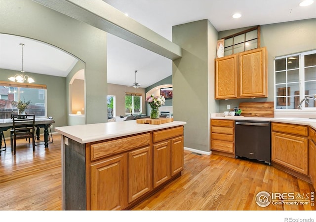 kitchen with dishwasher, a sink, light countertops, light wood-type flooring, and vaulted ceiling