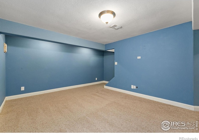 empty room with carpet, a textured ceiling, and baseboards