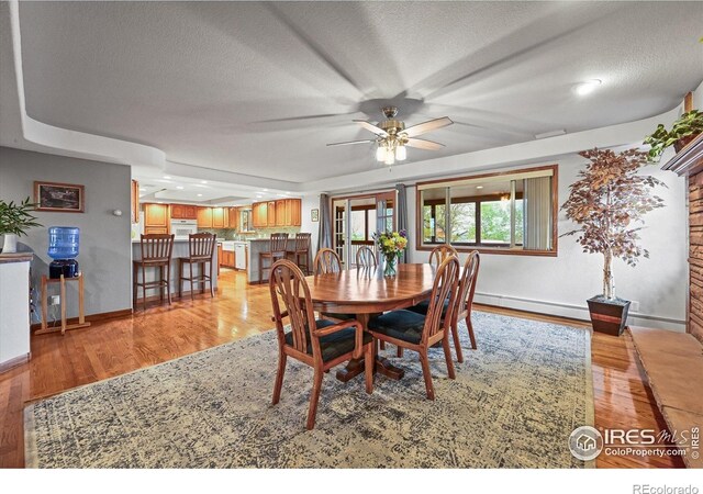 14531 Country Hills Dr, Brighton, CO 80601 - dining room featuring a baseboard radiator, a textured ceiling, baseboards, light wood-style flooring, and a ceiling fan