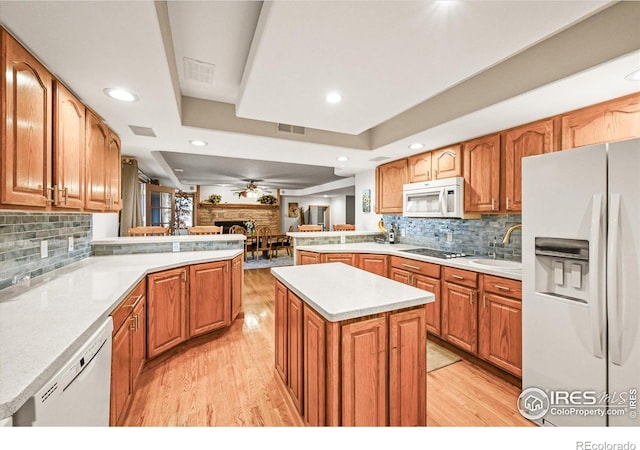 14531 Country Hills Dr, Brighton, CO 80601 - kitchen featuring white appliances, a peninsula, a fireplace, light wood-style floors, and a sink