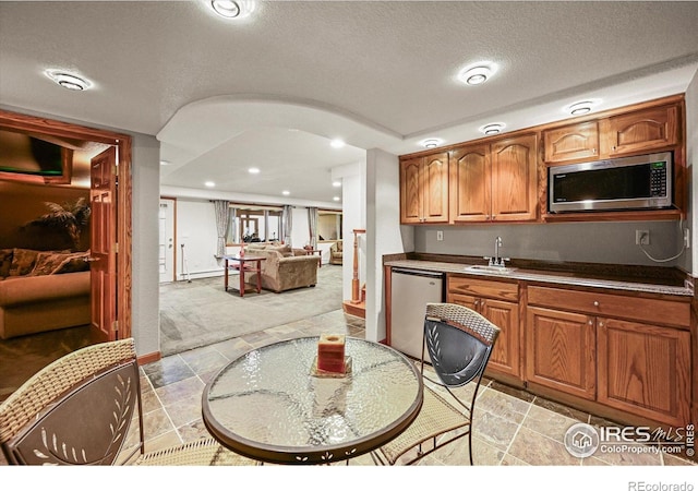 14531 Country Hills Dr, Brighton, CO 80601 - kitchen with dishwasher, stainless steel microwave, a sink, brown cabinets, and light carpet