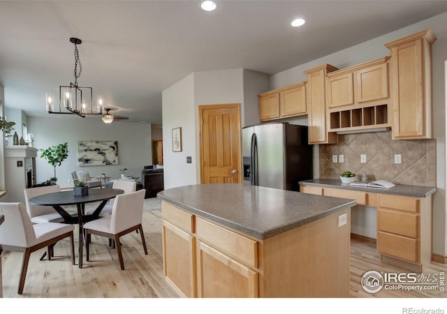 kitchen featuring stainless steel fridge, light brown cabinets, dark countertops, light wood-style floors, and a chandelier