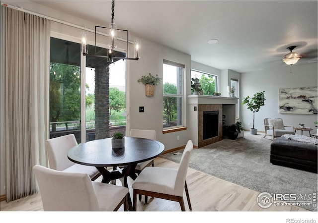 dining space featuring light wood-style floors, a chandelier, a fireplace, and baseboards
