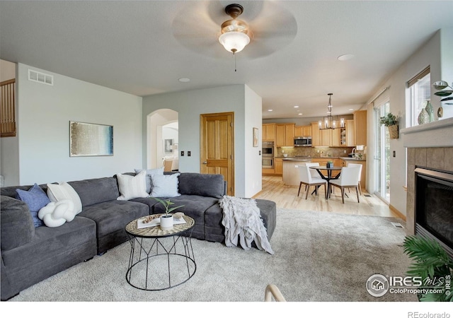 living area with a chandelier, arched walkways, a ceiling fan, recessed lighting, and light wood finished floors